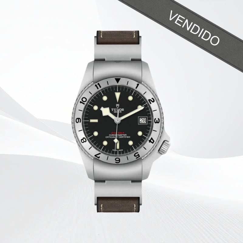 Reloj TUDOR con esfera negra, bisel con numeración y correa de cuero marrón.